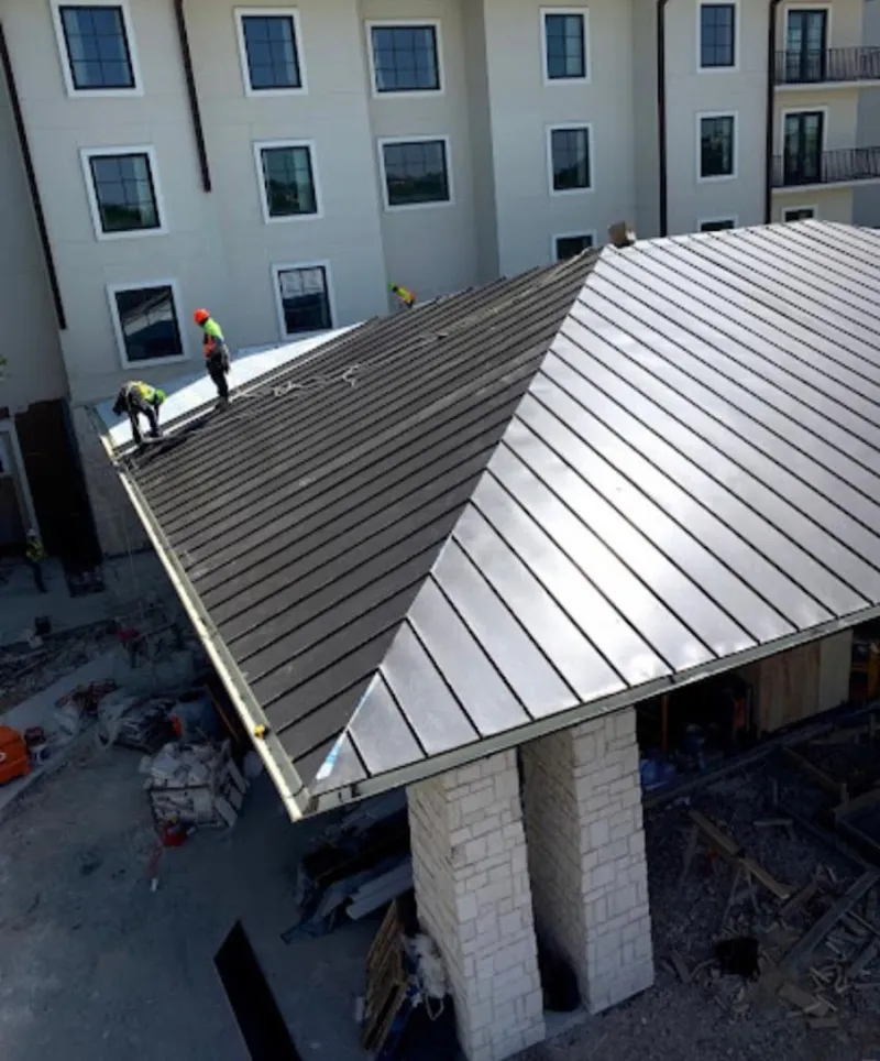 Crew installing standing seam metal roof panels on a commercial project in Fallbrook